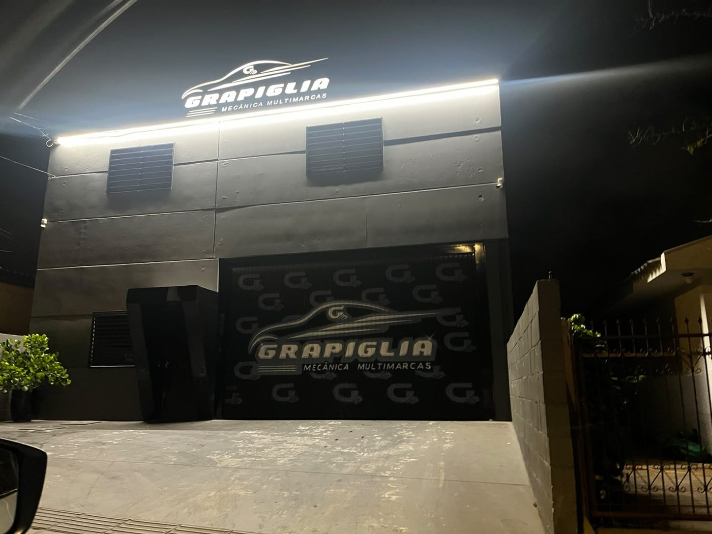 Fachada da Grapiglia iluminada à noite, com o letreiro da marca